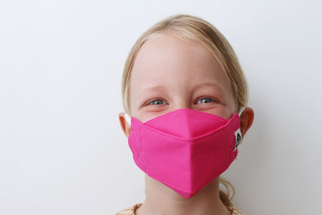 girl wearing bright pink reusable travel face mask by Earth Worthy.