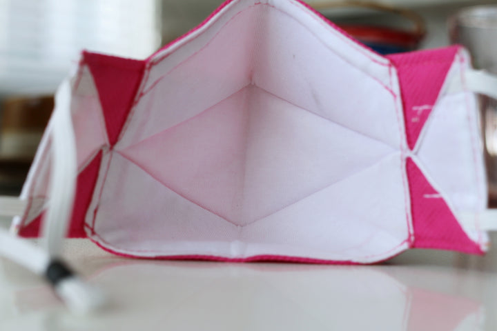 the inside of and earth worthy reusable facemask in pink. The mask has a cotton lining for comfort and behind the cotton layer is the filter to keep you safe.